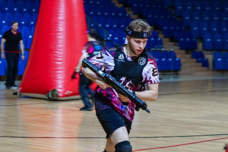 Игрок LASERWAR в динамике с оружием у красного препятствия.